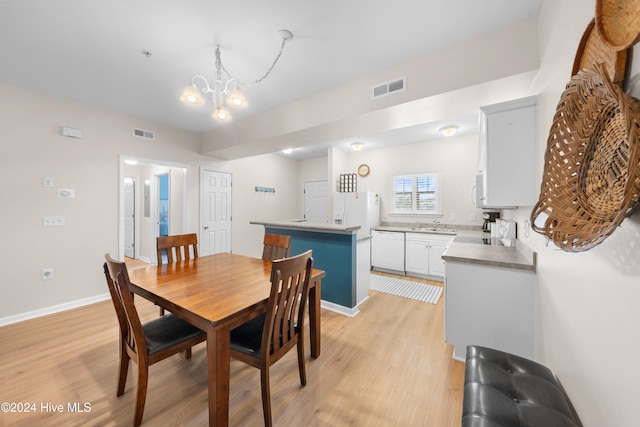 dining room with a chandelier, sink, and light wood-type flooring