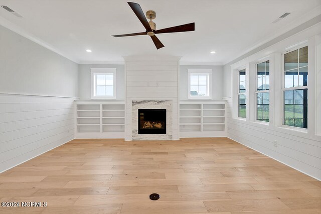 unfurnished living room with light hardwood / wood-style floors, plenty of natural light, and wooden walls