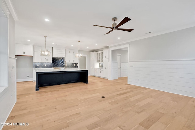 kitchen with a large island, decorative light fixtures, light wood-type flooring, and white cabinets