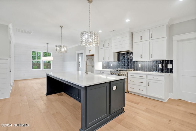 kitchen with light hardwood / wood-style flooring, white cabinetry, a center island with sink, and high end stainless steel range