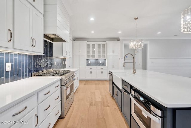 kitchen featuring sink, range with two ovens, light hardwood / wood-style floors, pendant lighting, and custom range hood