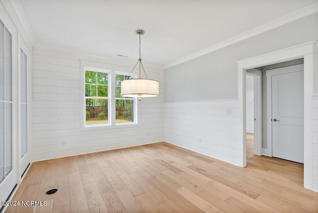 unfurnished dining area featuring wood walls, ornamental molding, and light hardwood / wood-style flooring