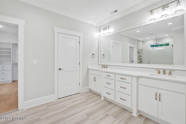 612 Waterstone Dr, Wilmington, NC 28411 - bathroom featuring a stall shower, double vanity, wood finished floors, crown molding, and a walk in closet