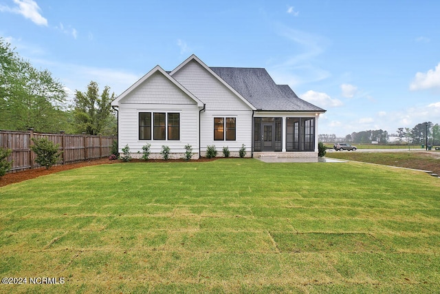 rear view of house featuring a yard and a sunroom