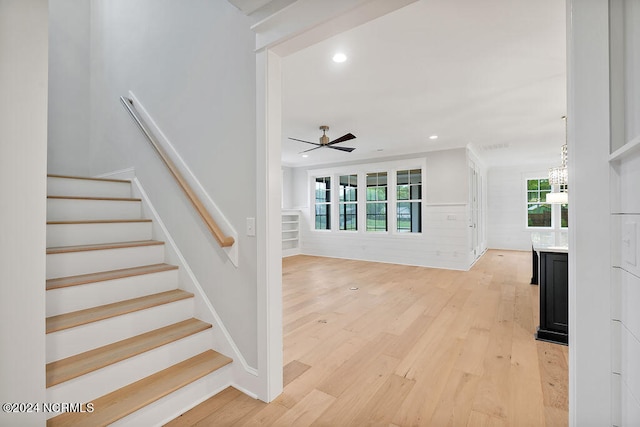 stairway featuring hardwood / wood-style flooring and ceiling fan with notable chandelier