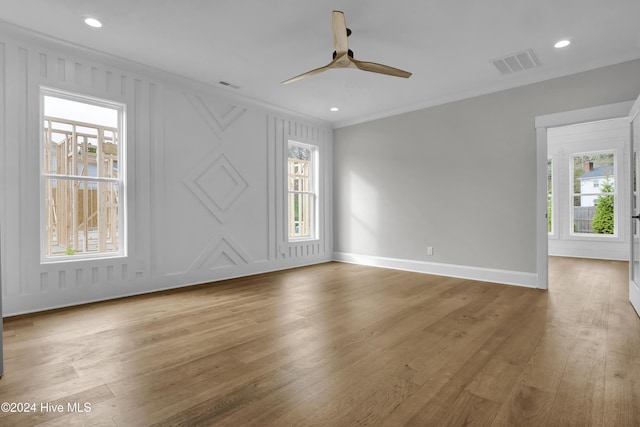 empty room featuring ceiling fan, a healthy amount of sunlight, wood-type flooring, and crown molding