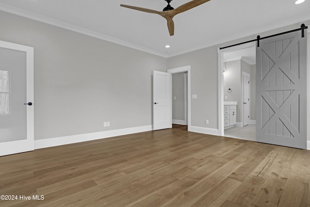 unfurnished bedroom with a barn door, ceiling fan, ornamental molding, and connected bathroom