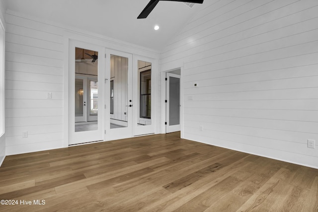 spare room with ceiling fan, wood walls, and vaulted ceiling