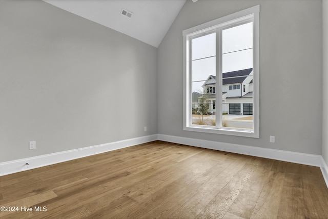 empty room featuring a healthy amount of sunlight, light wood-type flooring, and lofted ceiling