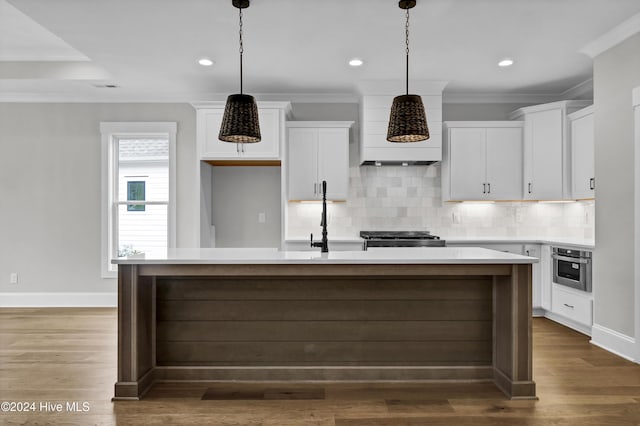 kitchen featuring white cabinetry, a kitchen island with sink, and hanging light fixtures