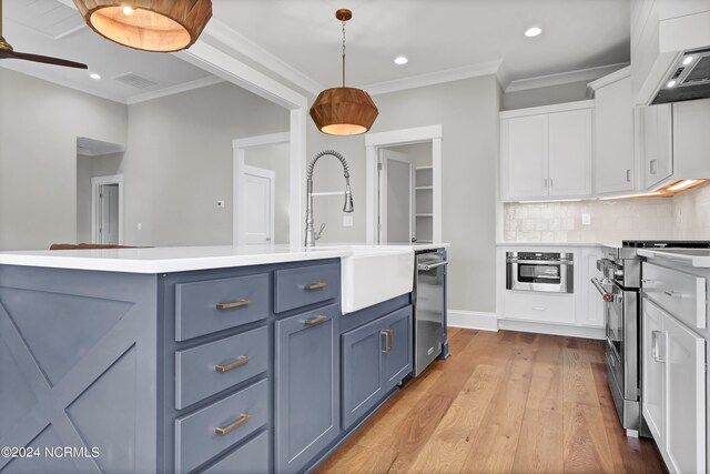 kitchen featuring white cabinetry, appliances with stainless steel finishes, decorative light fixtures, and light wood-type flooring