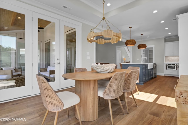 dining area with sink, crown molding, light hardwood / wood-style flooring, and french doors