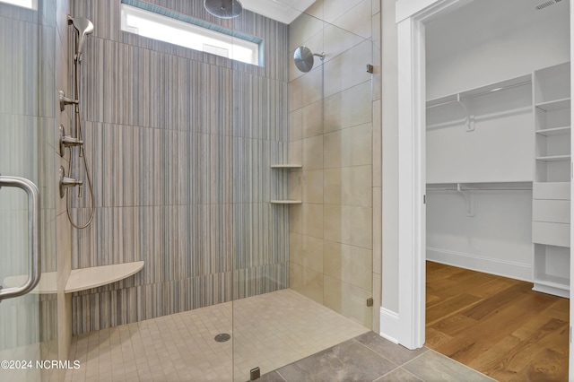 bathroom with a shower with shower door and wood-type flooring