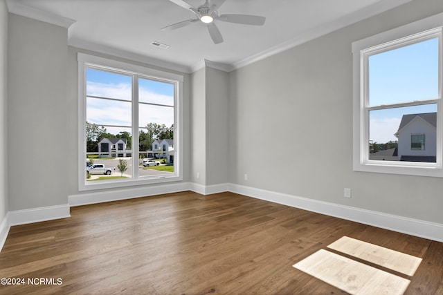 empty room with ornamental molding, hardwood / wood-style floors, ceiling fan, and a wealth of natural light