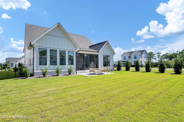 rear view of house featuring a patio area, a lawn, and a sunroom