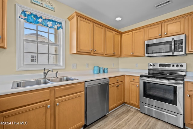 kitchen with appliances with stainless steel finishes, sink, and light hardwood / wood-style floors