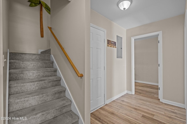 stairs featuring electric panel and hardwood / wood-style floors