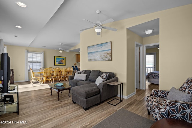 living room featuring ceiling fan, a healthy amount of sunlight, lofted ceiling, and light hardwood / wood-style flooring