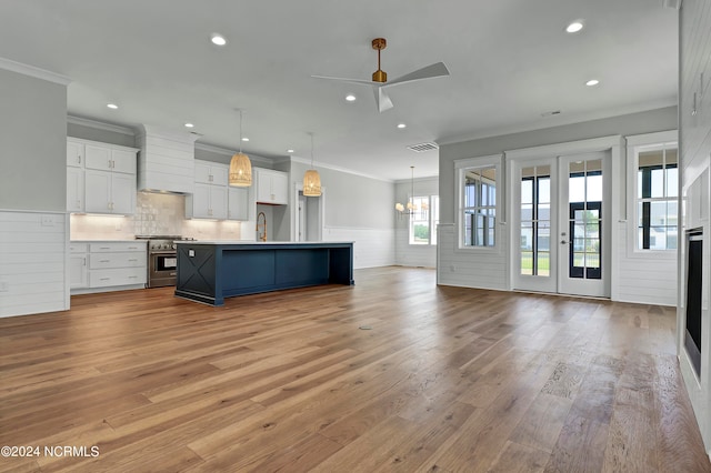 kitchen with stainless steel range, a large island, pendant lighting, light wood-type flooring, and white cabinets