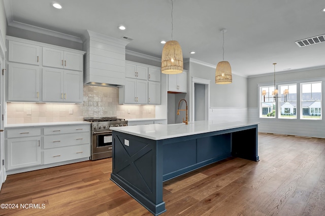 kitchen with stainless steel range, custom range hood, light hardwood / wood-style flooring, an island with sink, and white cabinetry