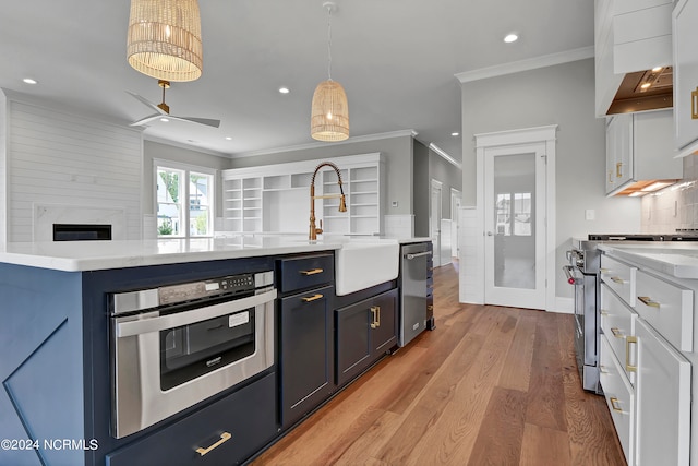 kitchen with light hardwood / wood-style flooring, stainless steel appliances, crown molding, pendant lighting, and white cabinetry