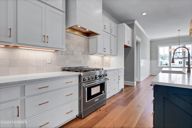 kitchen with white cabinetry, stainless steel stove, custom range hood, light hardwood / wood-style floors, and crown molding