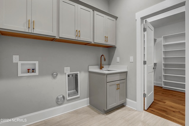 laundry room featuring cabinets, gas dryer hookup, hookup for a washing machine, light hardwood / wood-style flooring, and sink