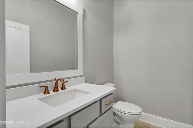 bathroom with vanity, toilet, and hardwood / wood-style flooring