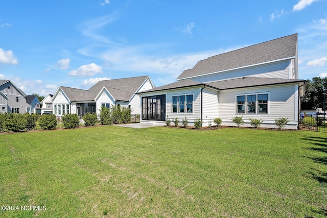 rear view of house featuring a sunroom and a lawn