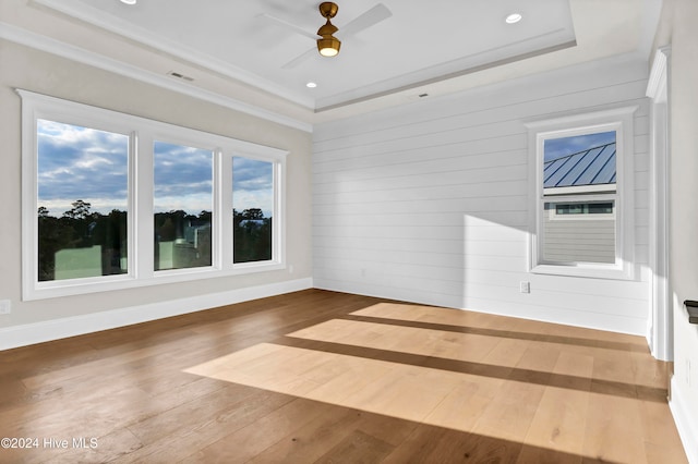 unfurnished room with ceiling fan, a raised ceiling, and hardwood / wood-style floors