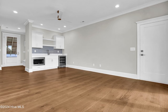 unfurnished living room featuring wine cooler, ornamental molding, and dark hardwood / wood-style floors