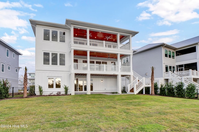 back of house featuring ceiling fan, a lawn, and a balcony