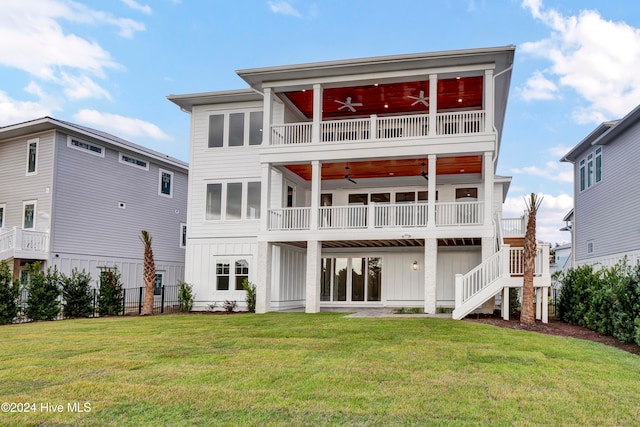 rear view of property with a balcony, a yard, and ceiling fan