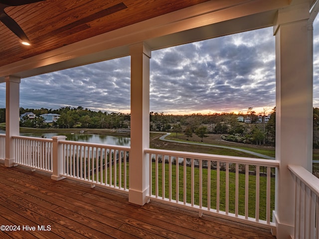 deck at dusk with a yard and a water view