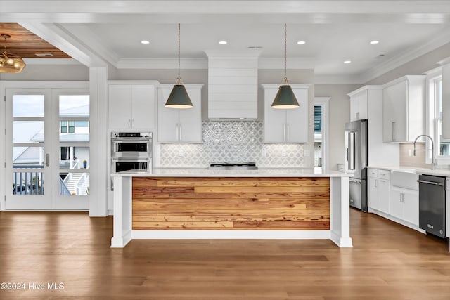 kitchen featuring dark hardwood / wood-style flooring, appliances with stainless steel finishes, a kitchen island, white cabinetry, and pendant lighting