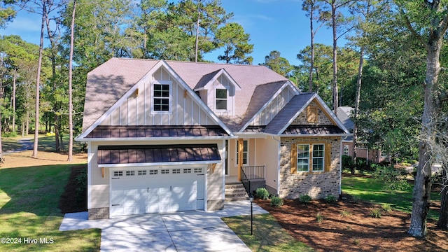 craftsman-style home with board and batten siding, a standing seam roof, a front lawn, and concrete driveway