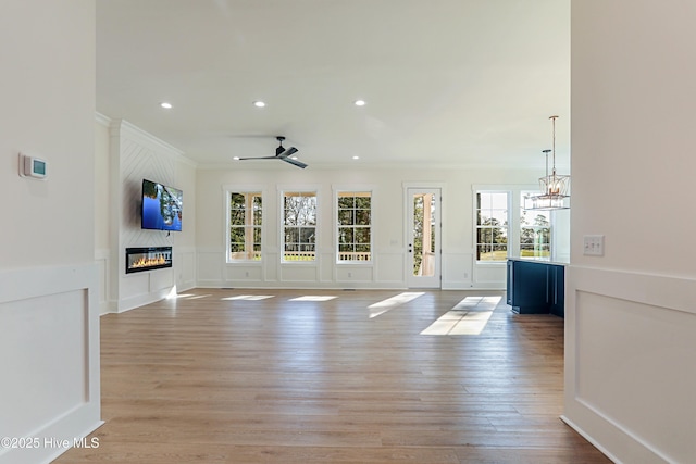 unfurnished living room with plenty of natural light, a decorative wall, crown molding, and a large fireplace