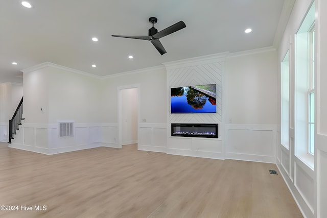 living room with a fireplace, ceiling fan, light hardwood / wood-style flooring, and crown molding