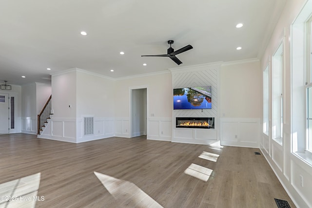 unfurnished living room with a decorative wall, a large fireplace, ornamental molding, visible vents, and recessed lighting