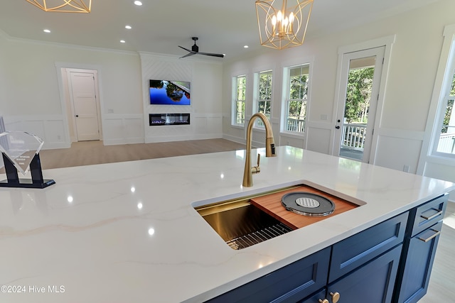 kitchen featuring a decorative wall, light stone counters, a sink, blue cabinets, and open floor plan