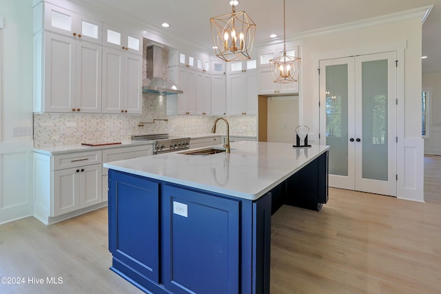 kitchen featuring light wood finished floors, french doors, white cabinets, and wall chimney range hood