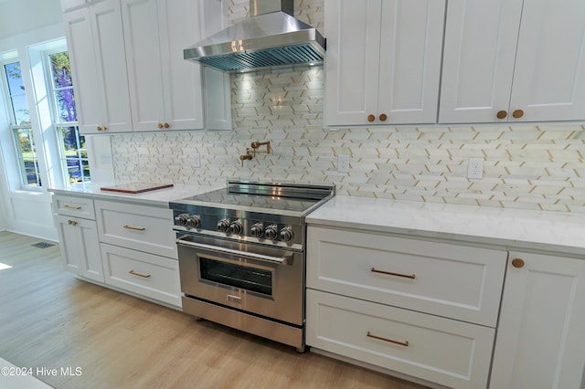 interior details featuring white cabinetry, light stone countertops, stainless steel stove, and backsplash