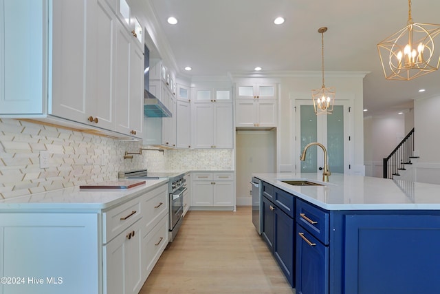 kitchen with white cabinets, stainless steel appliances, a sink, blue cabinetry, and a notable chandelier
