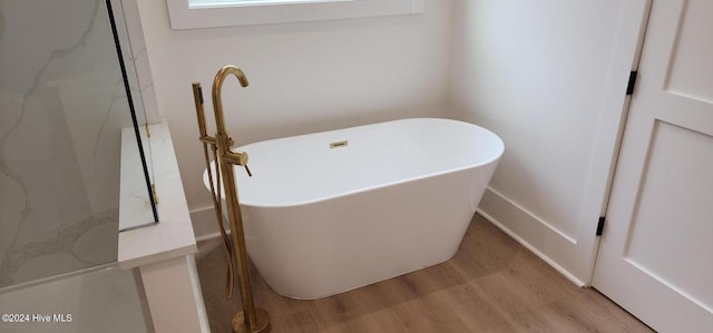 bathroom with a freestanding tub and wood finished floors