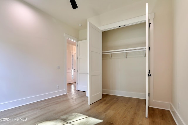 unfurnished bedroom with light wood-type flooring, a ceiling fan, baseboards, and a closet