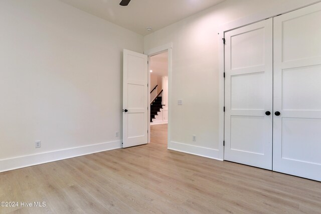 unfurnished bedroom with a closet, a walk in closet, ceiling fan, and light hardwood / wood-style flooring