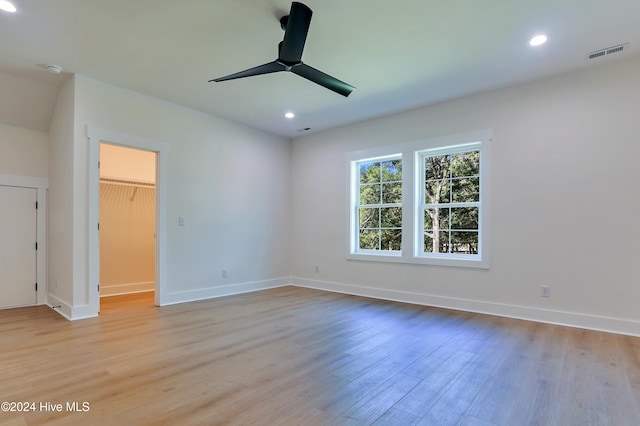 bedroom featuring light hardwood / wood-style flooring, ceiling fan, a walk in closet, and a closet