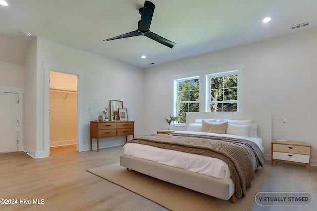 bedroom with a spacious closet, ceiling fan, light wood finished floors, and recessed lighting