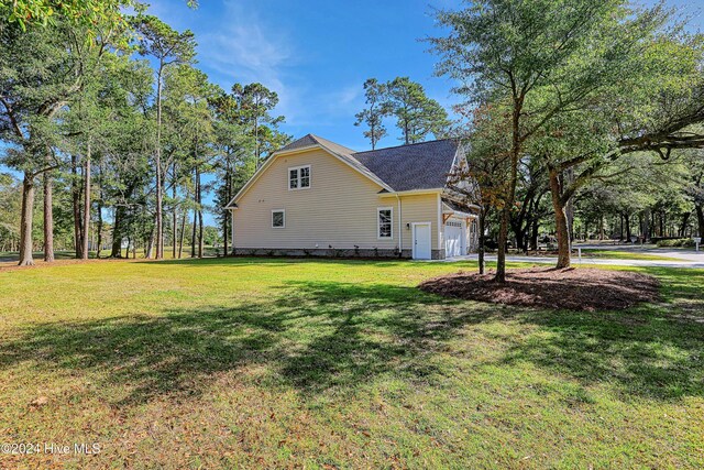 view of side of property with roof with shingles, a yard, and a garage