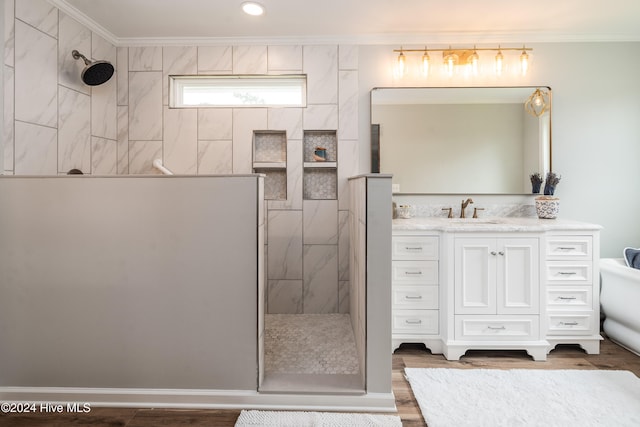 bathroom featuring vanity, crown molding, hardwood / wood-style flooring, and tiled shower